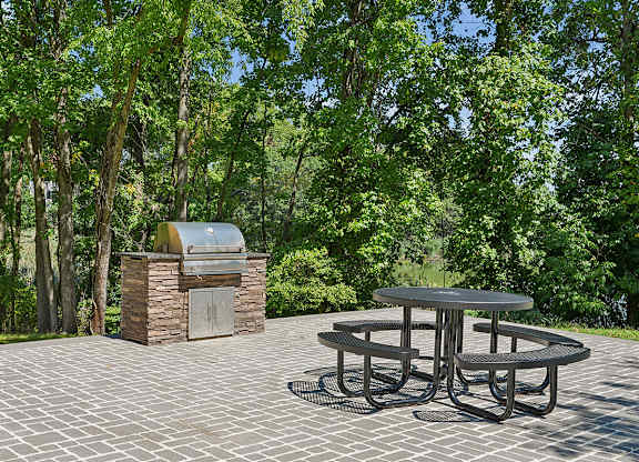 A picnic table is surrounded by trees and a stone structure.