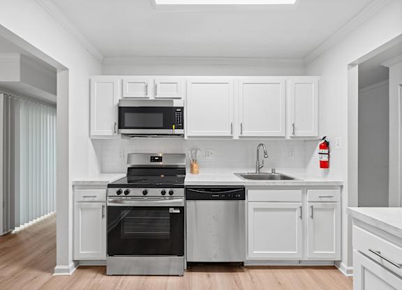 A modern kitchen with white cabinets and stainless steel appliances.