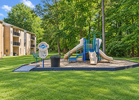 A playground with a blue slide and a sign in the foreground.