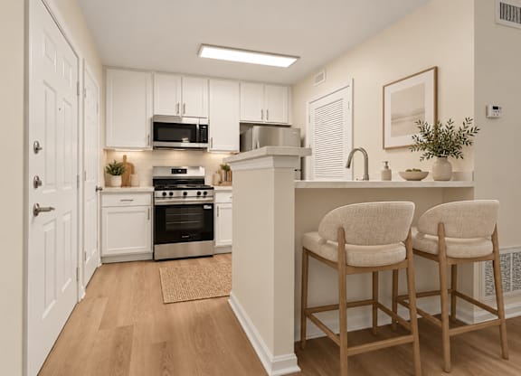 Modern kitchen with breakfast bar and upholstered stools at The Courts at Fair Oaks Apartments, Fairfax, VA 22030