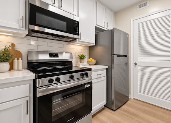 Modern kitchen with stainless steel range and white cabinetry at The Courts at Fair Oaks Apartments, Fairfax, 22030