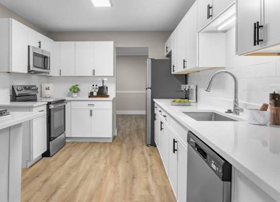 A modern kitchen with white cabinets and a wooden floor. at Riverchase Landing Apartments, Hoover, 35244
