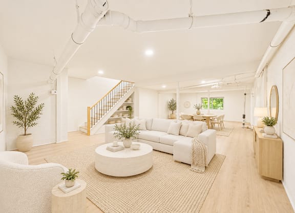 A white living room with a staircase in the background.