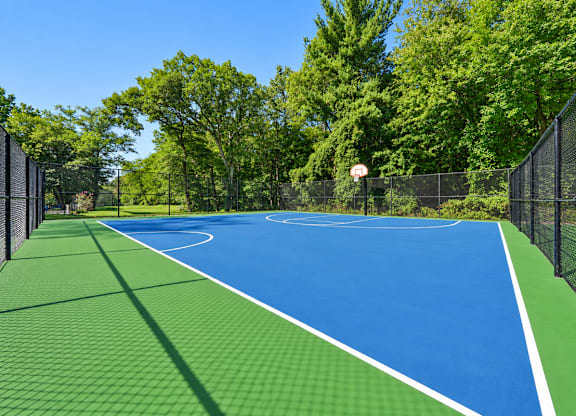 A blue and green tennis court surrounded by a black fence.