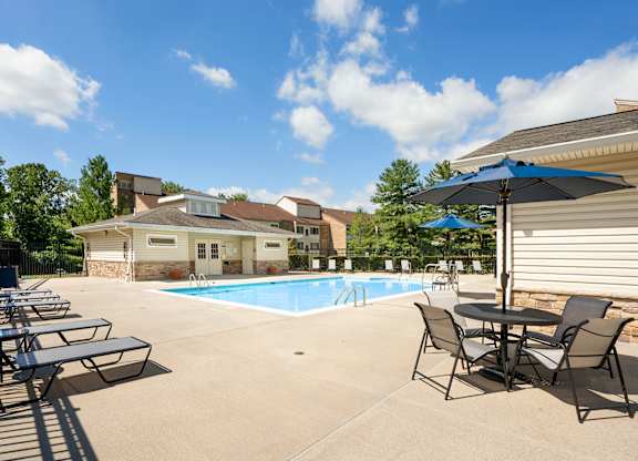 Outdoor swimming pool with lounge chairs and umbrellas at The at Elmwood Terrace Apartments, Frederick, MD