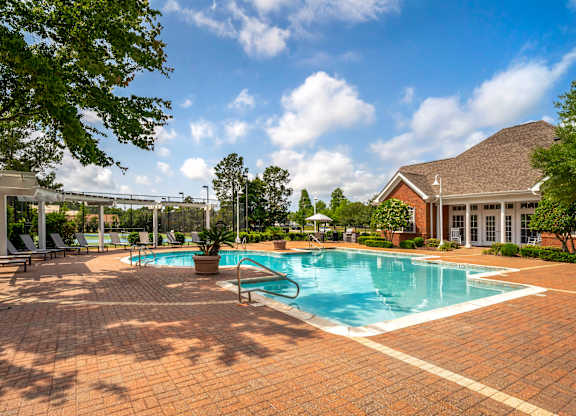 A large outdoor swimming pool surrounded by a brick patio.