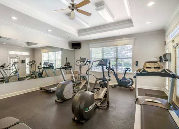 A spacious gym with a variety of exercise equipment and a ceiling fan.