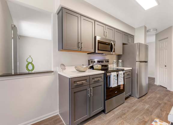 A kitchen with dark brown cabinets and stainless steel appliances. at The Apartments at Owings Run, Maryland
