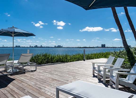a deck with chairs and an umbrella overlooking the water at The Hamilton, Miami, FL