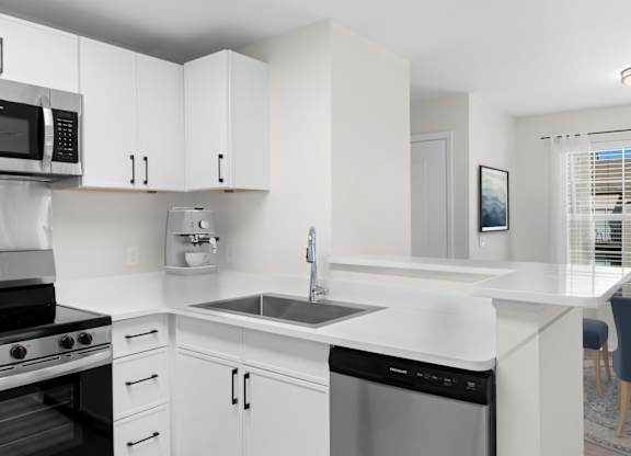 A modern kitchen with white cabinets and appliances. at Reflection Pointe, Flowood, Mississippi