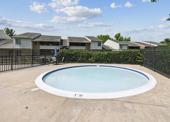 A round above ground pool surrounded by a black fence.
