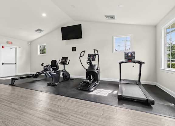 A spacious home gym with a treadmill, rowing machine, and stationary bike.