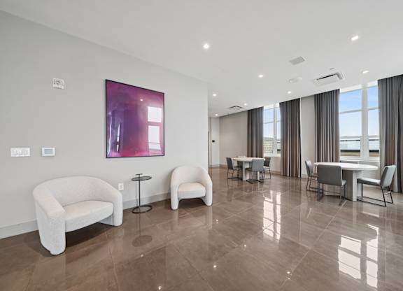 A living room with a white sofa, two chairs, and a table.