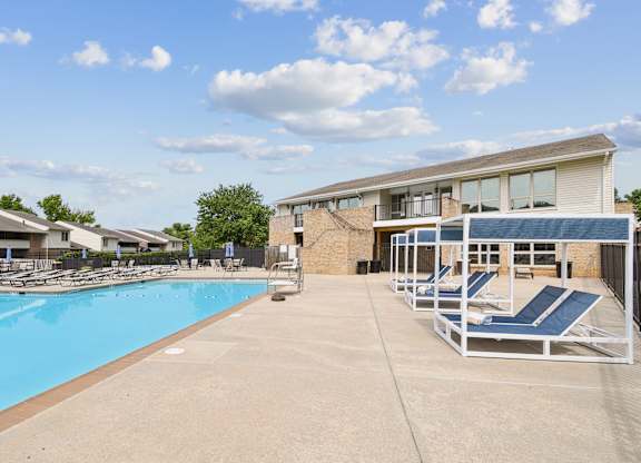 A swimming pool with sun loungers and a building in the background.