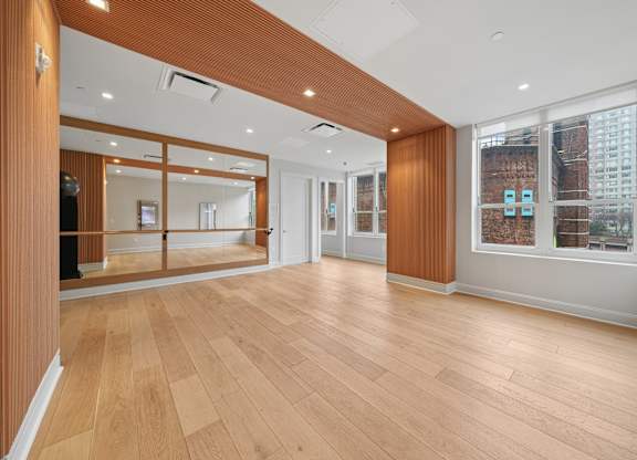 A spacious room with wooden floors and a large mirror on the wall.