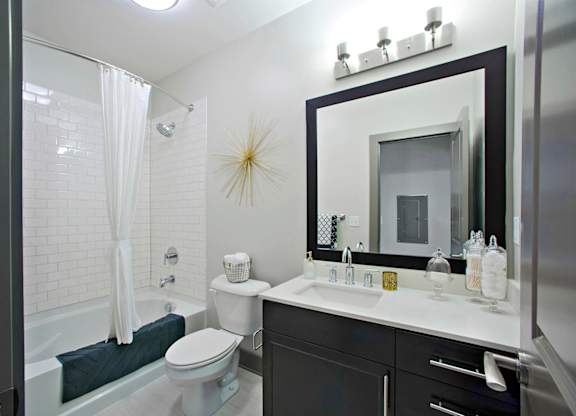 a bathroom with a white toilet next to a bathtub with a shower curtain at The Addison,Louisiana