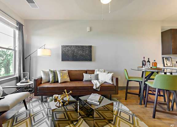 a living room and dining room with a couch and chairs and a table with a chair  at The Addison, Baton Rouge, LA