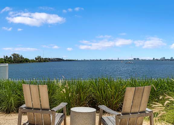 Waterfront lounge chairs overlooking bay with city skyline at The Hamilton Apartments, Miami