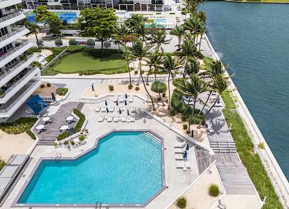 Waterfront pool deck with palm trees and lounge chairs at The Hamilton Apartments, Miami, 33137