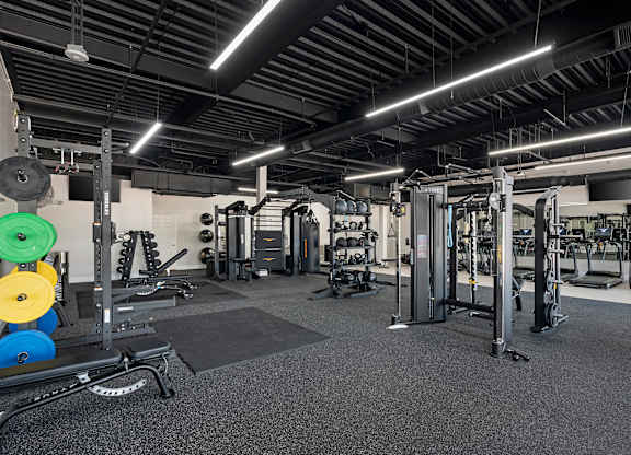 a view of the fitness center with weights and cardio equipment in a gym at Villaggio Apartments, Bossier City, Louisiana
