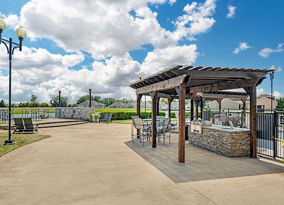 an outdoor patio with tables and chairs and a pergola at Villaggio Apartments, Bossier City