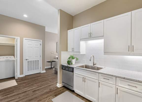 a white kitchen with white cabinets and a stainless steel sink at Villaggio Apartments, Bossier City, LA