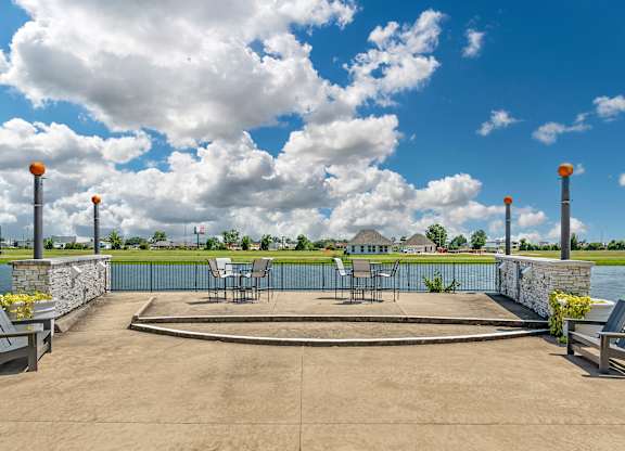 a patio with tables and chairs overlooking a body of water at Villaggio Apartments, Louisiana