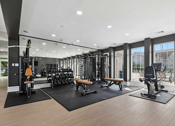 A gym with a variety of equipment including weights and cardio machines.