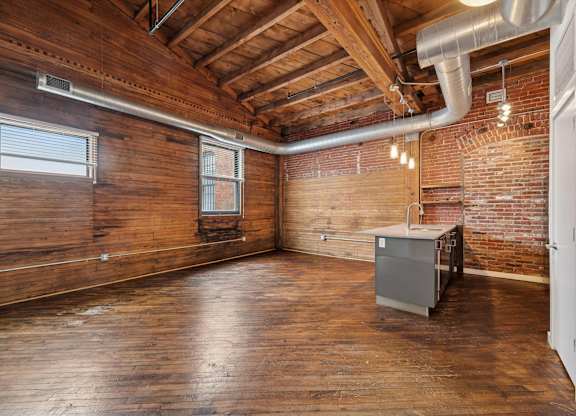 A room with wooden walls and a brick wall with a window and a radiator.