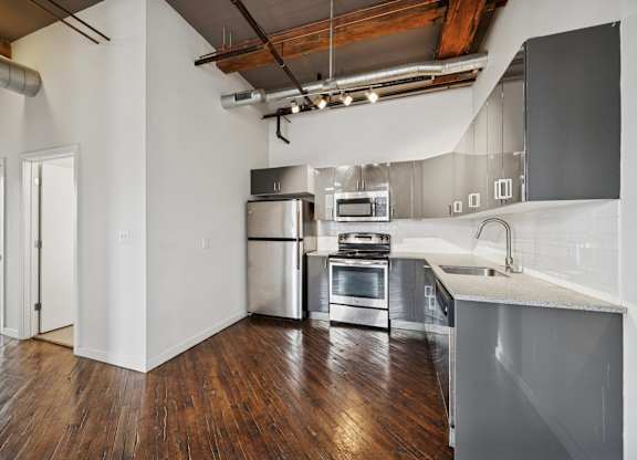 A kitchen with a stainless steel refrigerator, oven, and sink.