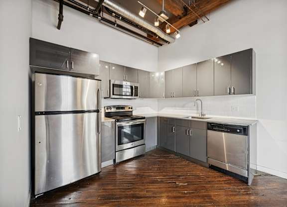 A kitchen with stainless steel appliances and wooden floors.