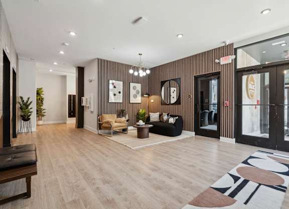 A modern office lobby with a wooden floor and a black bench.