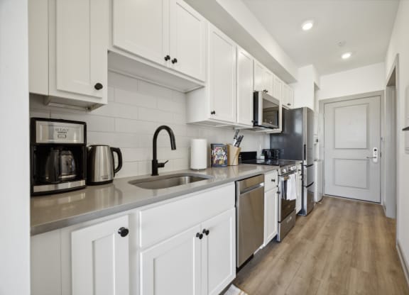 a kitchen with white cabinets and stainless steel appliances at The Commons On Ludlow Apartments, Philadelphia, PA