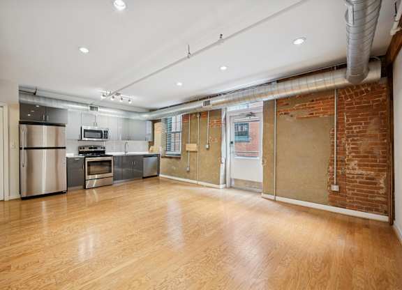 A kitchen with wooden floors and a brick wall.