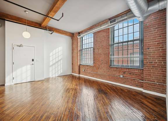 A room with wooden floors and a brick wall.