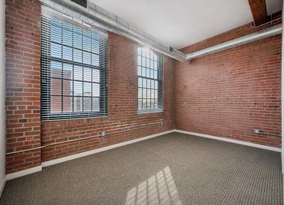 A room with a brick wall and a window with blinds.