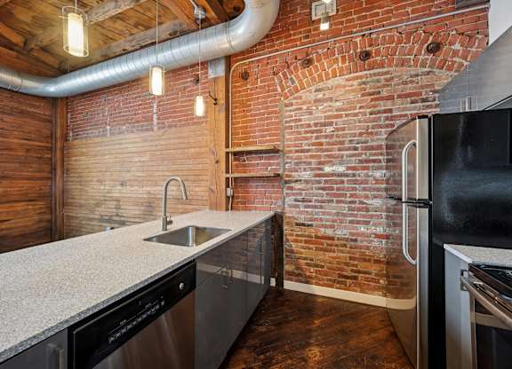 A kitchen with a brick wall and stainless steel appliances.