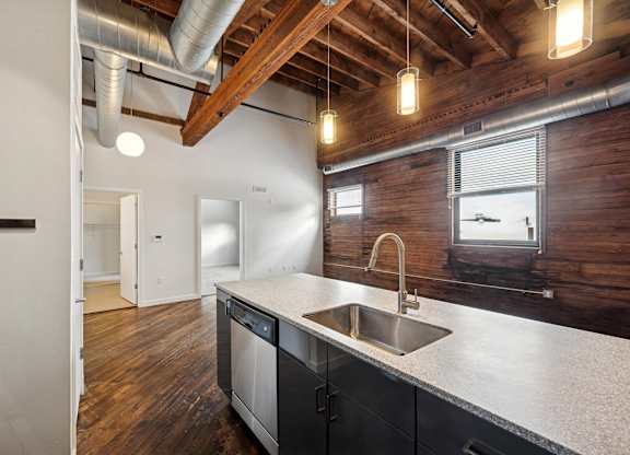 A kitchen with a wooden wall and a stainless steel sink.