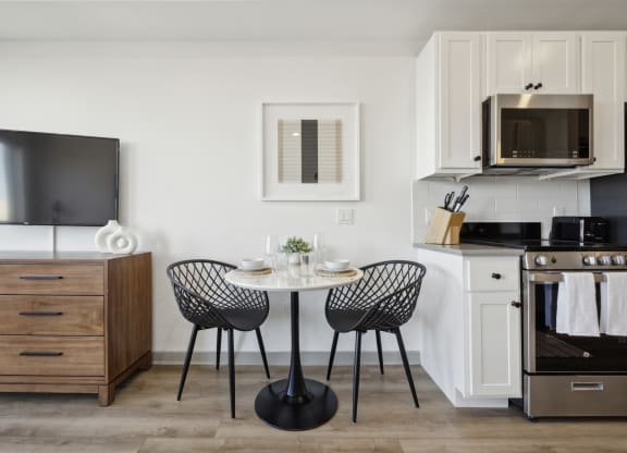 a kitchen and dining area with a small table and chairs and a microwave at The Commons On Ludlow Apartments, Pennsylvania 19104