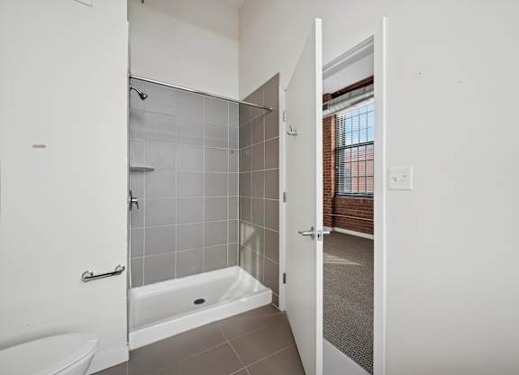 A white bathroom with a glass shower door and a white toilet.