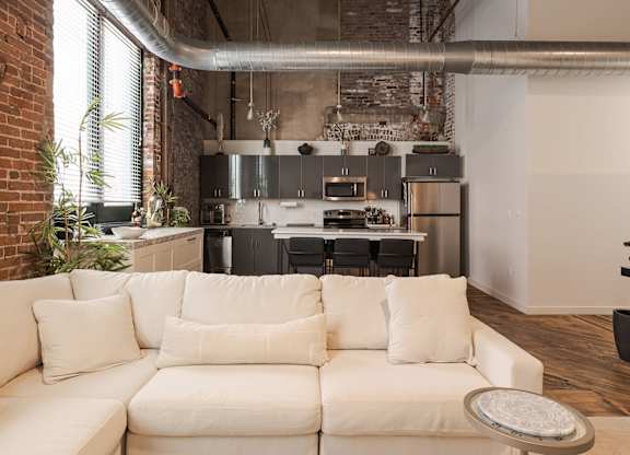 A white couch with a round tray on it in front of a kitchen.