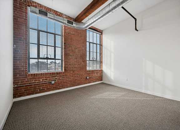 A room with a brick wall and a window with blinds.