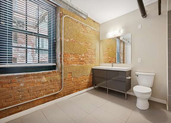 A bathroom with a toilet, sink, and a window.