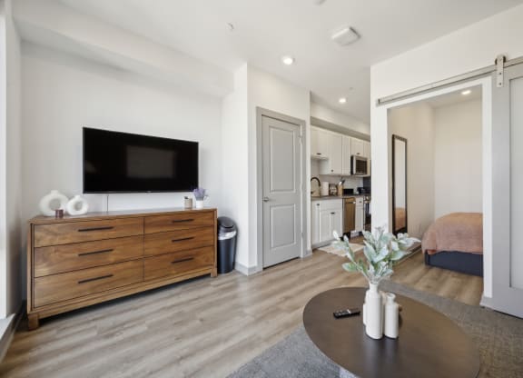 a living room with a tv and a table at The Commons On Ludlow Apartments, Philadelphia, PA