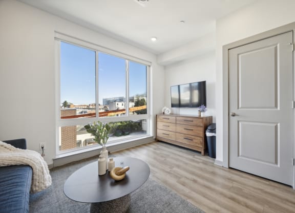 a living room with a couch and a table and a tv at The Commons On Ludlow Apartments, Philadelphia, PA