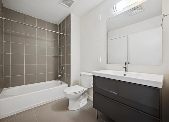 A white bathtub sits next to a toilet in a bathroom.