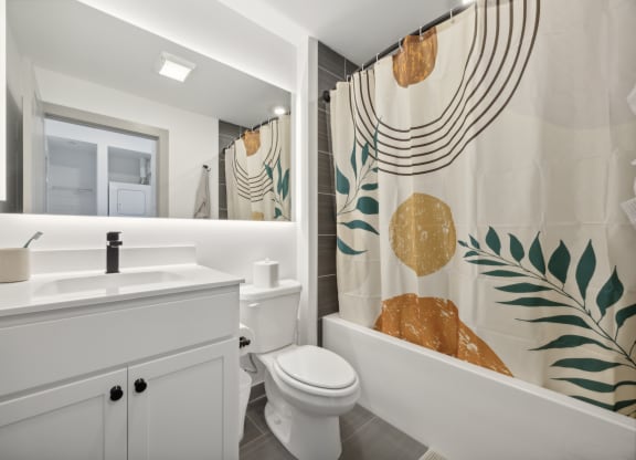 a bathroom with a shower curtain and a toilet and a sink at The Commons On Ludlow Apartments, Philadelphia, Pennsylvania