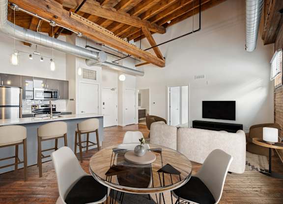 A modern open plan living and kitchen area with a dining table and chairs.