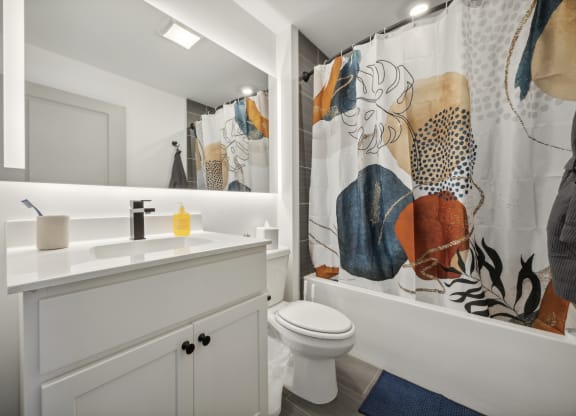 a bathroom with a shower curtain and a sink and a toilet at The Commons On Ludlow Apartments, Philadelphia