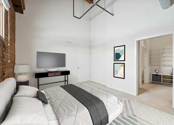 A bedroom with a white bed and a grey blanket.